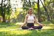 © Prathankarnpap - Peaceful millennial woman wearing sportswear having meditation session, sitting in lotus position on green park with sunlight