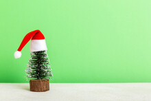One Small Christmas Tree With Santa Hat On Colored Background. New Year Decoration With Copy Space