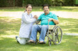 © GAJENDRRA BHATI  - Indian caregiver nurse taking care of senior male patient in a wheelchair outdoor at park, Asian doctor help and support elderly mature older people. rehabilitation and health care.