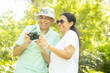 © GAJENDRRA BHATI  - Happy senior indian couple tourist holding camera taking photos and view them together at summer park. Mature people travel and holidays.