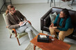 © AnnaStills - High angle view of psychotherapist discussing problems with patient during psychotherapy session at office
