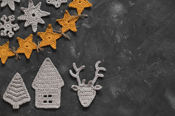 Wall Mural - Christmas composition with handmade nordic crochet toys. Christmas tree, house, deer, snowflakes, yellow star garland on a dark grey background. Copy space.