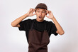 © Molasidn - Handsome barista asian man wearing brown apron and black t-shirt isolated over white background shocked with surprise and amazed expression