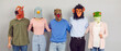 Crazy funny team of happy people wearing strange eccentric Halloween carnival animal masks standing in row and hugging each other. Group portrait on studio background. Teamwork, support, unity concept
