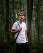 close up portrait photography of a young photographer guy with camera on a neck strap in a forest