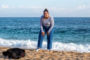 Wall Mural - Woman and dog playing on the beach