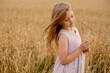 © Тамара Киреева - a beautiful blonde girl in a pink linen dress stands in a wheat field and touches her with her hands