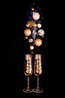 Glasses of champagne and golden shiny holiday decor, balloons on black background with sparkles