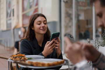 Sitting in restaurant, texting on smartphones. Boyfriend, girlfriend on date browsing mobile phone Bored with cellphones