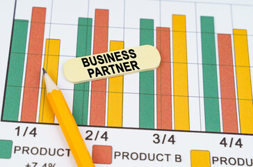 On business reports - diagrams there is a pencil and a sticker with the inscription - BUSINESS PARTNER