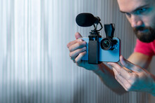 A Young Man Sets Up His Phone To Shoot A Video. A Lens And Microphone Are Installed On The Phone. Smartphone Videography Concept