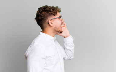 Wall Mural - young adult caucasian man profile view, looking happy and excited, shouting and calling to copy space on the side