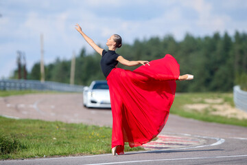 Dancing ballerina in red flying skirt on the road