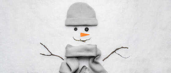 Funny snowman made of hat, scarf and tree branches on snow