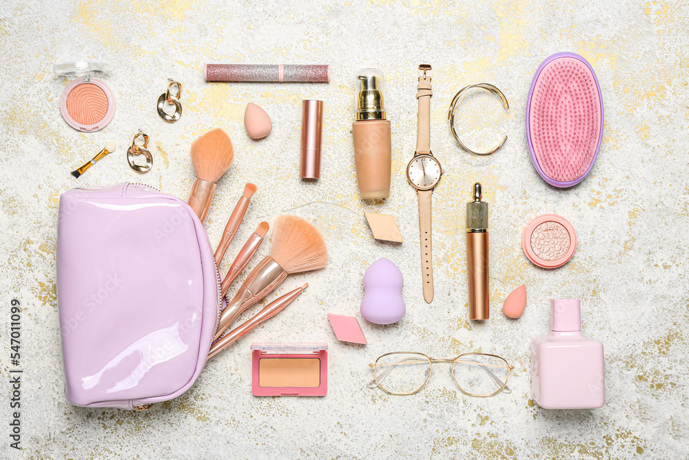 Bag with makeup brushes, cosmetics and accessories on grunge background