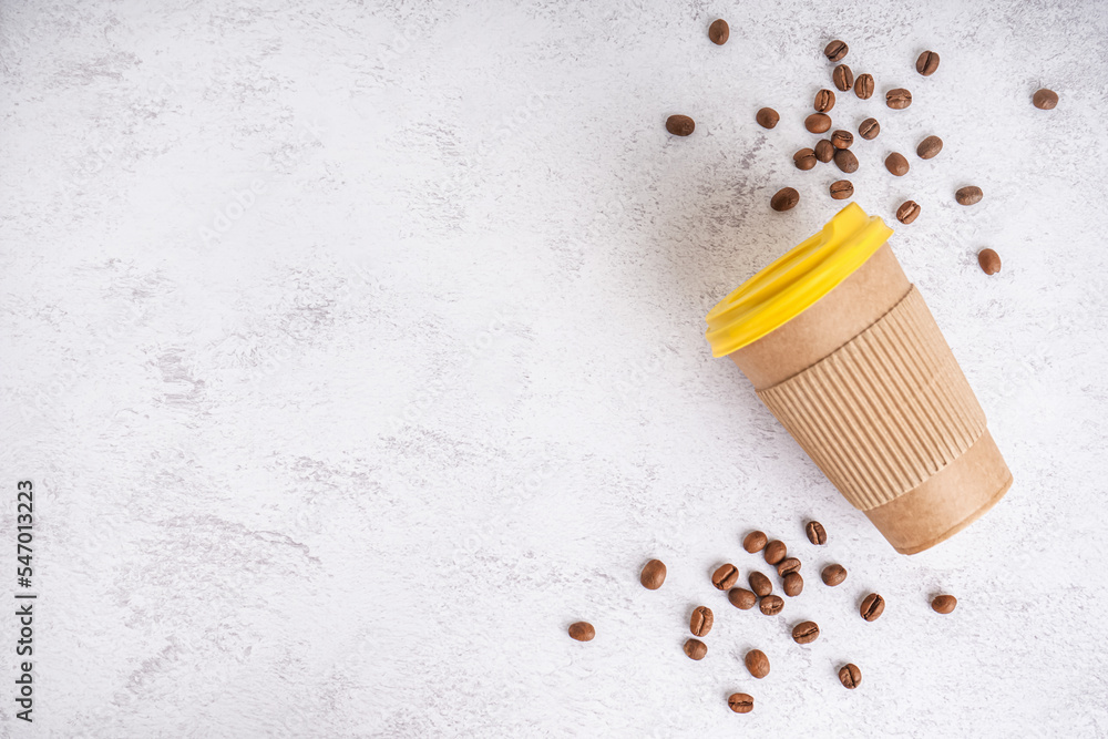 Paper cup and coffee beans on light background