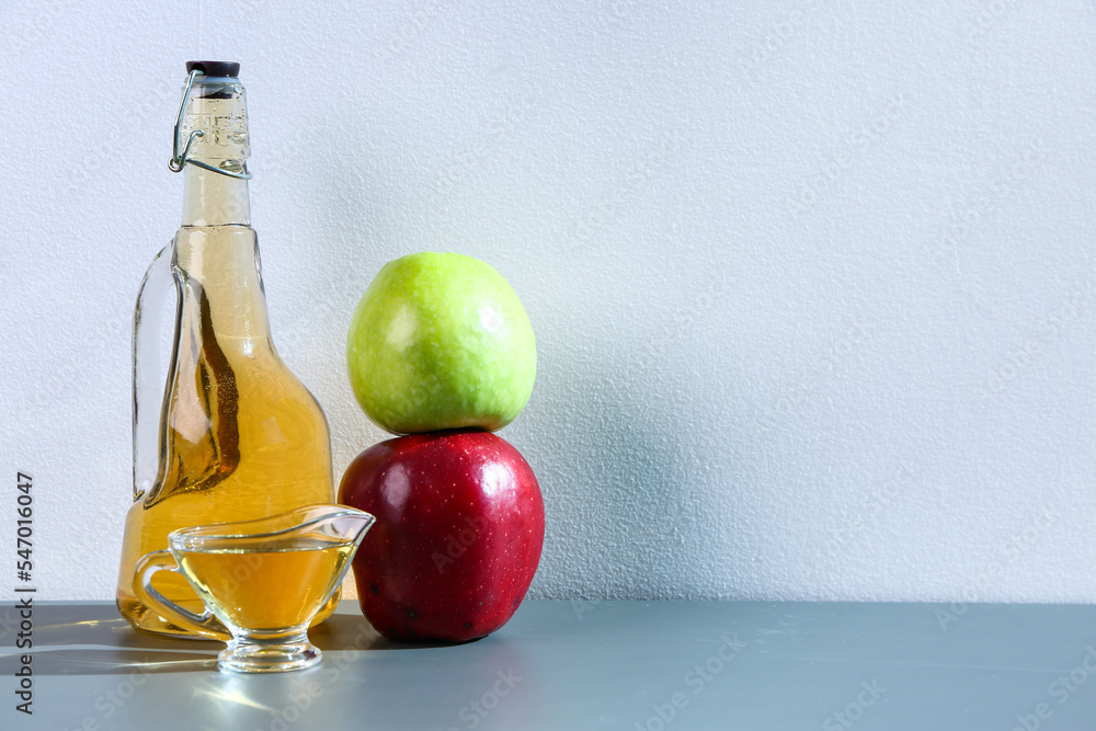 Bottle and gravy boat of apple cider vinegar on table