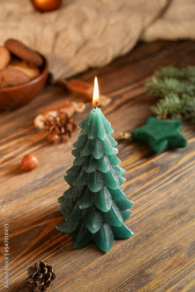 Burning Christmas tree candle on wooden table, closeup