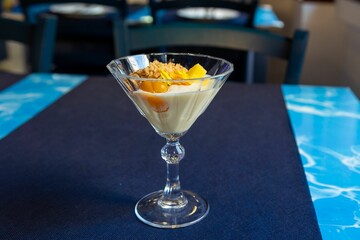 Canvas Print - Glass of cream with fruit and crumbled tart on a blue table in a cafe