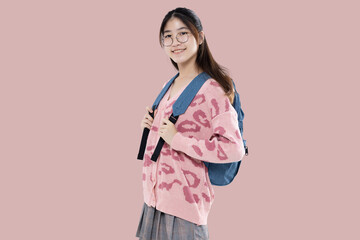 Wall Mural - Happy Asian ethnicity teen girl hold backpack isolated on pastel pink background. Education in high school college concept.