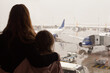 © millaf - Family, mother and little doughter watching plane flying from airport