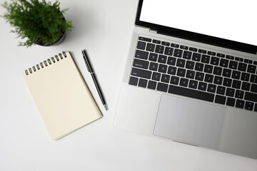 Top view on white background with notebook, pen and laptop computer