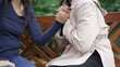 © Marco - Woman helping DEPRESSED female friend hugging in SUPPORT. Two women embrace sitting on park bench