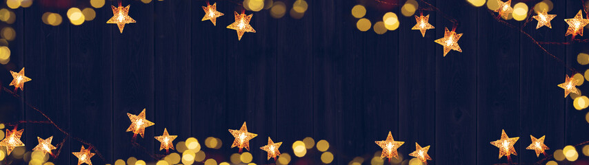 Christmas celebration decoration background banner panorama - Frame made of golden star light chain and bokeh lights on dark blue wooden boards wall texture