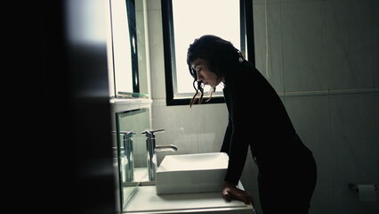 Wall Mural - Troubled young woman standing in front of bathroom mirror suffering from mental disorder