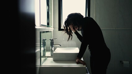 Troubled young woman standing in front of bathroom mirror suffering from mental disorder