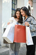 Two Asian women enjoy shopping together at the city square shopping center.