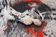 © ullision - Young artistically abstract painted naked woman with black and white paint, lying on the red, black, gray designed floor in the studio