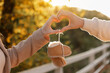 © Andriy Medvediuk - Man and pregnant wife are doing heart gesture with hands and holding warm baby shoes on nature autumn background. Future parents waiting for the baby. The concept of Mother's Day and Women's Day.