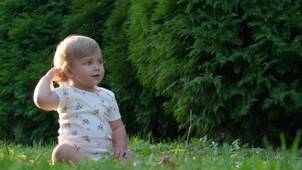 Wall Mural - Cute little girl sitting on green grass