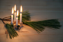 Four Small Advent Candles Placed On A Cookie Cutter In Star Shape And A Pine Branch On A Wooden Table, Minimalist Decoration In The Christmas Season, Copy Space, Selected Focus