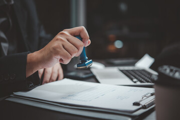 Hand hold stamping rubber business document invoice bill financial on desk.