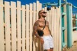 Attractive topless man with tattoos standing next to a wooden fence with a blue sky