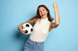 Portrait of young beautiful woman posing with happy winning look isolated over blue studio background. Football fan