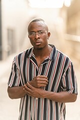 Wall Mural - Vertical shot of a young attractive sexy black male with a striped shirt and sunglasses posing