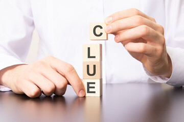 Poster - wooden cubes with the word CLUE, the hand puts a cube with letter C.