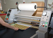 Electric industrial laminator for applying film to paper in the production shop is working