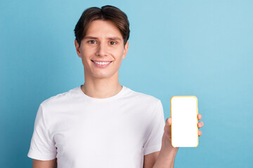 Handsome guy showing smartphone with blank screen demonstrating copy space for app website design standing in blue background