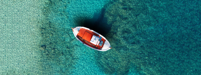 Wall Mural - Aerial drone ultra wide panoramic top view photo of red wooden traditional fishing boat in turquoise sea shore of Mykonos island, Cyclades, Greece