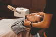 Hairdresser massages man face to improve hair growth and skin care. Preparing and softening beard for shaving with razor in barbershop vintage color