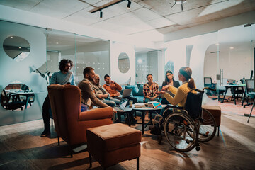 Businesswoman in wheelchair having business meeting with team at modern office. A group of young freelancers agree on new online business projects