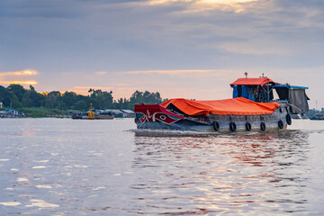 Wall Mural - A large covered barge cruising down a river at dawn in Chau Doc, Vietnam