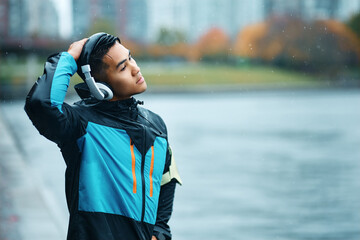 Athletic man stretching his neck while warming up for exercising outdoors in the rain.