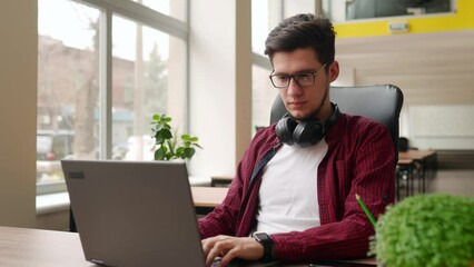 Wall Mural - young stylish freelancer working with laptop then looking at camera. office worker typing on pc, pos