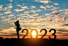 Silhouette Of Photographer Taking Photos In 2023 Years At Sunrise Or Sunset Background. Idea For Happy New Year 2022.
