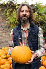 Poster - Bearded farmer with pumpkin on a background of a pile of pumpkins